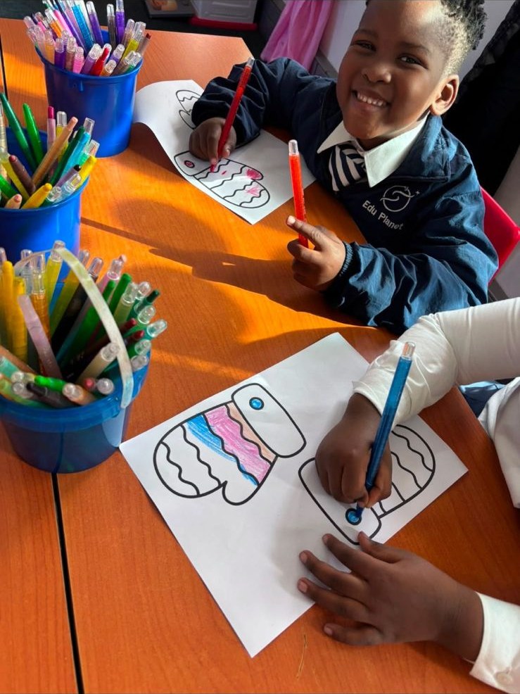 Two EduPlanet learners colouring at their desks during a foundation phase lesson.