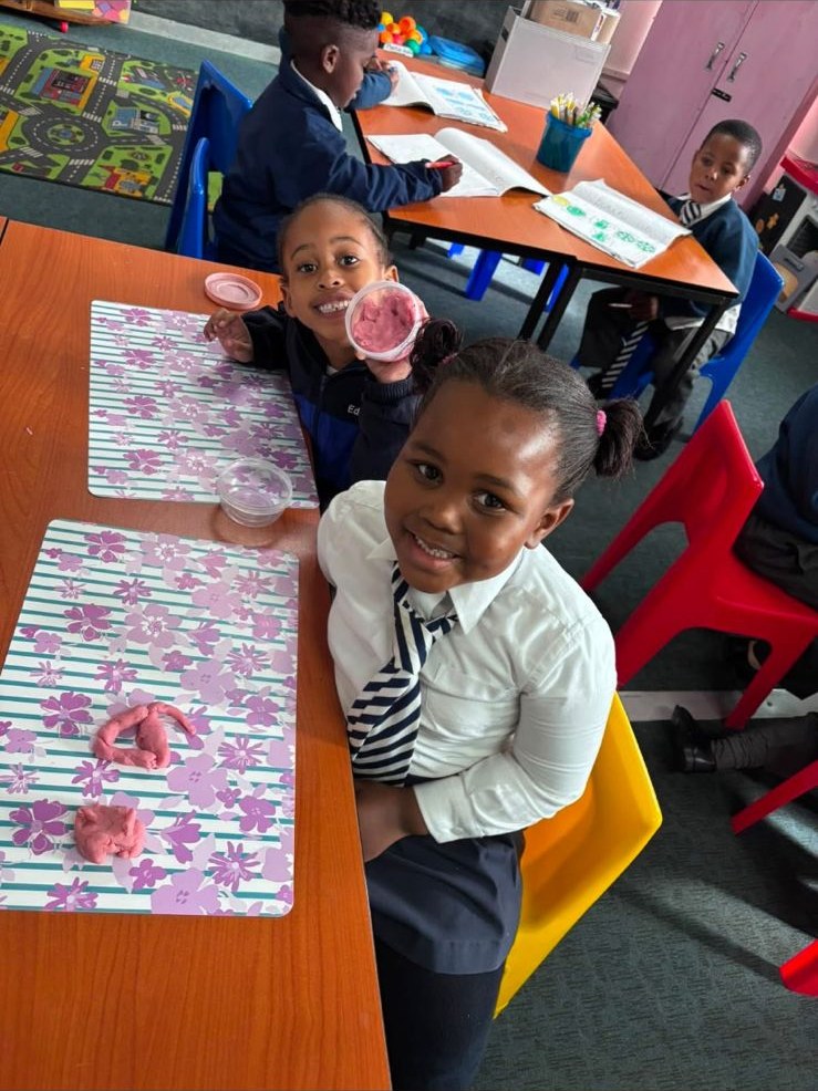 Young learners working with modelling clay at a classroom table.