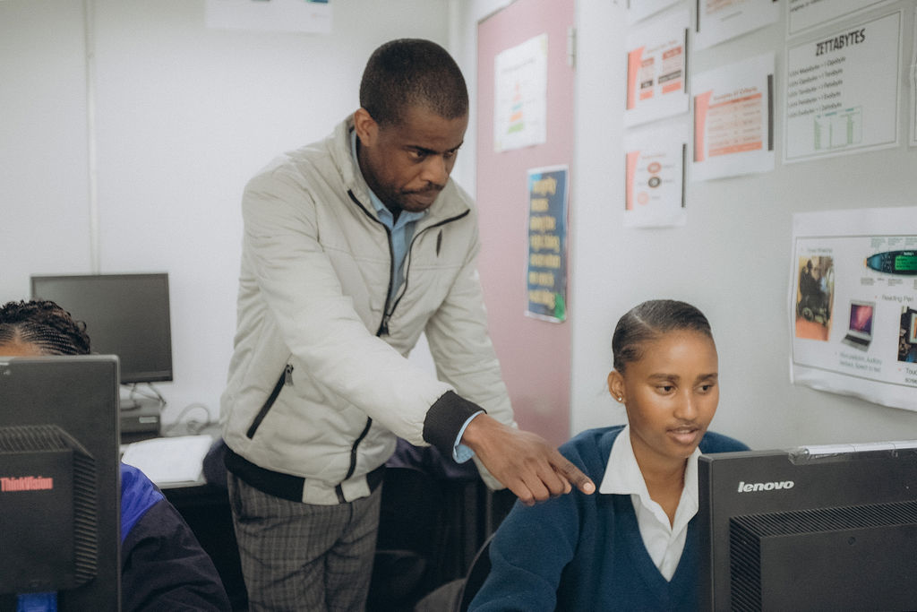 Teacher helping a learner at a computer workstation